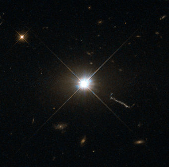A bright, star-shaped structure together with another star and small, faint galaxies A bright, star-shaped structure together with another star and small, faint galaxies