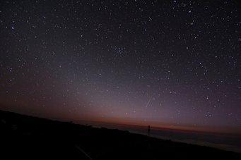 Picture of the night sky underlaid by a faint, oblique wedge-shaped glow and a shooting star Picture of the night sky underlaid by a faint, oblique wedge-shaped glow and a shooting star