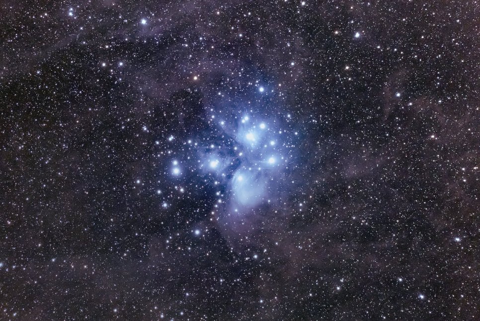 Long exposure close-up of the Pleiades, showing blueish nebulae around the brighter stars