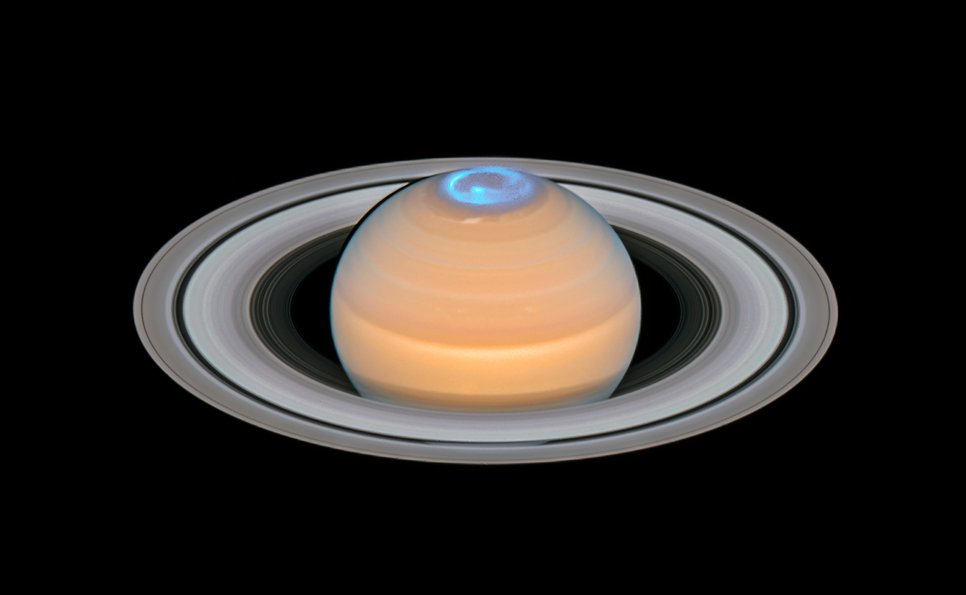 Close-up of the planet Saturn in visible light overlaid with a UV image showing auroras around the planet's north pole as a light blue ring