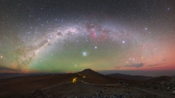 Panoramic view of the Milky Way as an arc over Paranal. The night sky is brightened by a green glow in the center and in red to the right edge Panoramic view of the Milky Way as an arc over Paranal. The night sky is brightened by a green glow in the center and in red to the right edge